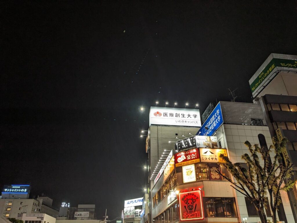 夜間に照明で表示された医療創生大学いわきキャンパスの大型ビル看板